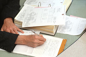 Eine Person füllt Formulare in einem Ordner aus