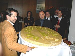 Mann schneidet riesigen Kuchen an.
