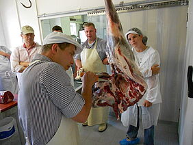 Metzger und Seminarteilnehmer beim Zerteilen von Fleisch