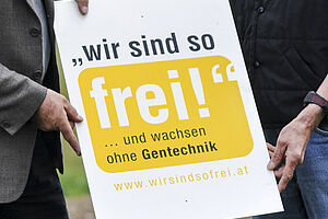 [Translate to Italienisch:] Zwei Menschen halten ein Poster mit der Aufschrift "Wir sind so frei und wachsen ohne Gentechnik"