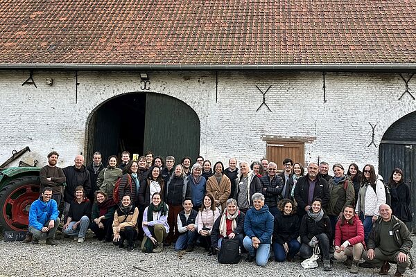A group of people in front of a barn.