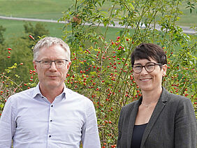 A man and a woman in front of a green landscape.