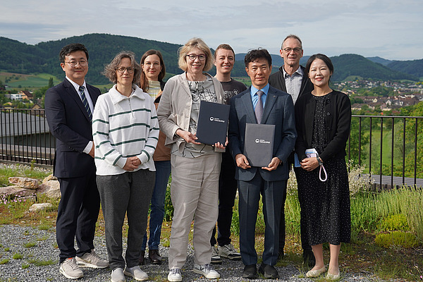 A group of people with a village and mountains in the background.