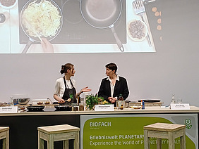 Zwei Frauen kochen auf Podium.