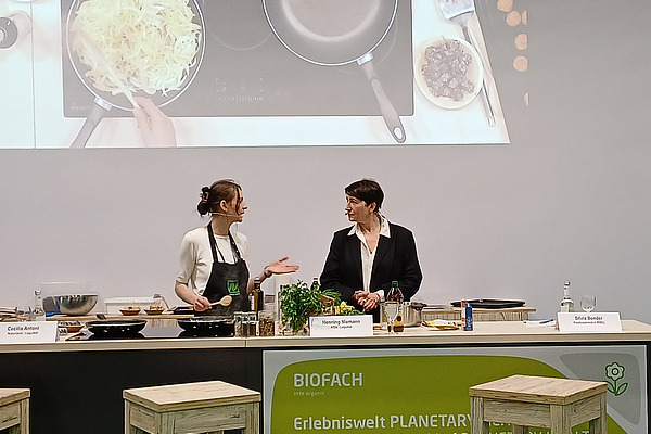 Zwei Frauen kochen auf Podium.