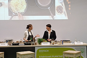 Zwei Frauen kochen auf Podium.