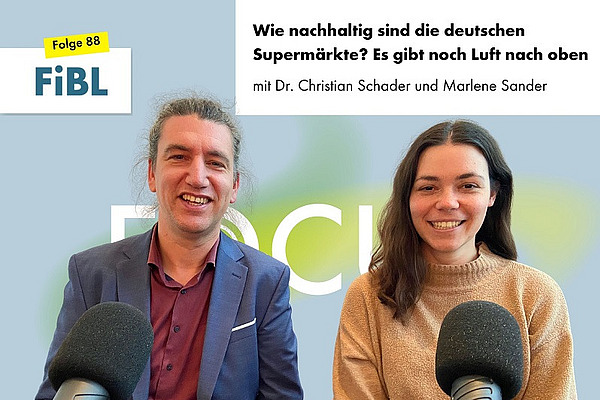 Ein Mann und eine Frau an Podcastmikrofonen.