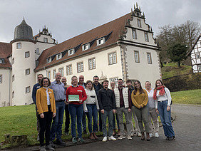 Gruppenfoto von Männern und Frauen vor einem Schloss. 