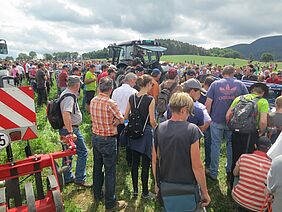 Un groupe de personnes se tient près d'un tracteur.