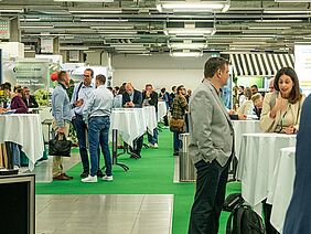 Eine Halle mit Menschen an Tischen.