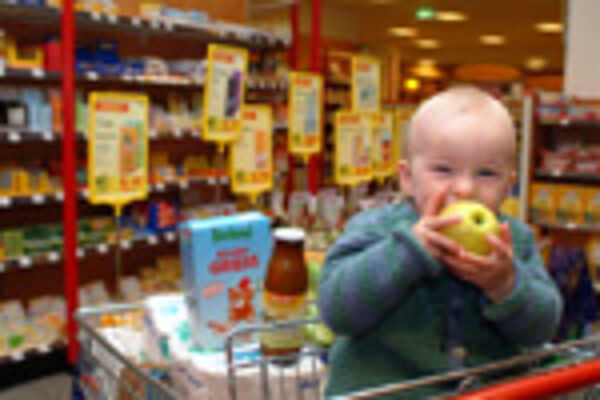 Kleinkind im Einkaufswagen mit Bio-Apfel