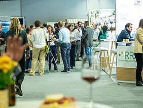 A hall with people at tables, and exhibitors.