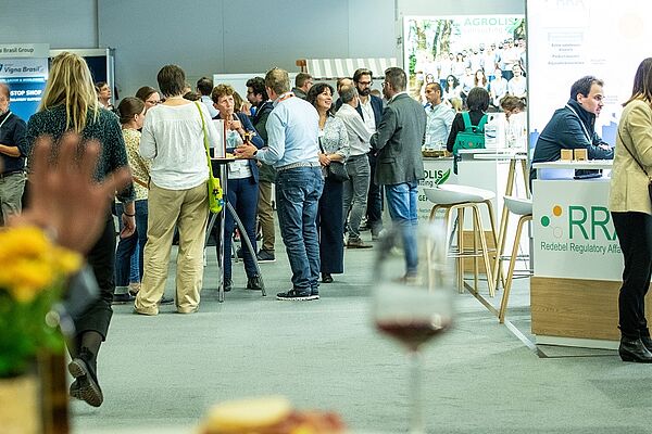 Eine Halle mit Menschen an Tischen und Ausstellern.