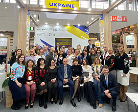 A group of about 40 people in front of a Ukraine stand.