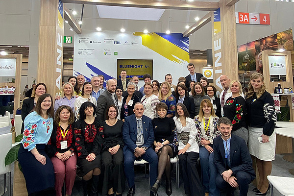 A group of about 40 people in front of a Ukraine stand.