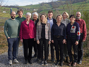 A group of people with a green hill in the background.