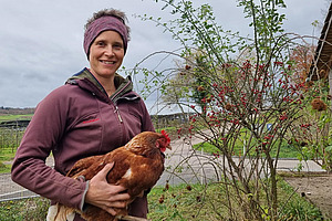 Frau mit Huhn auf dem Arm.